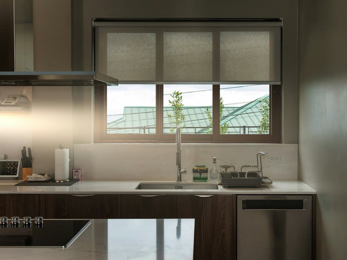A kitchen with a sink and dishwasher beside a bright window.