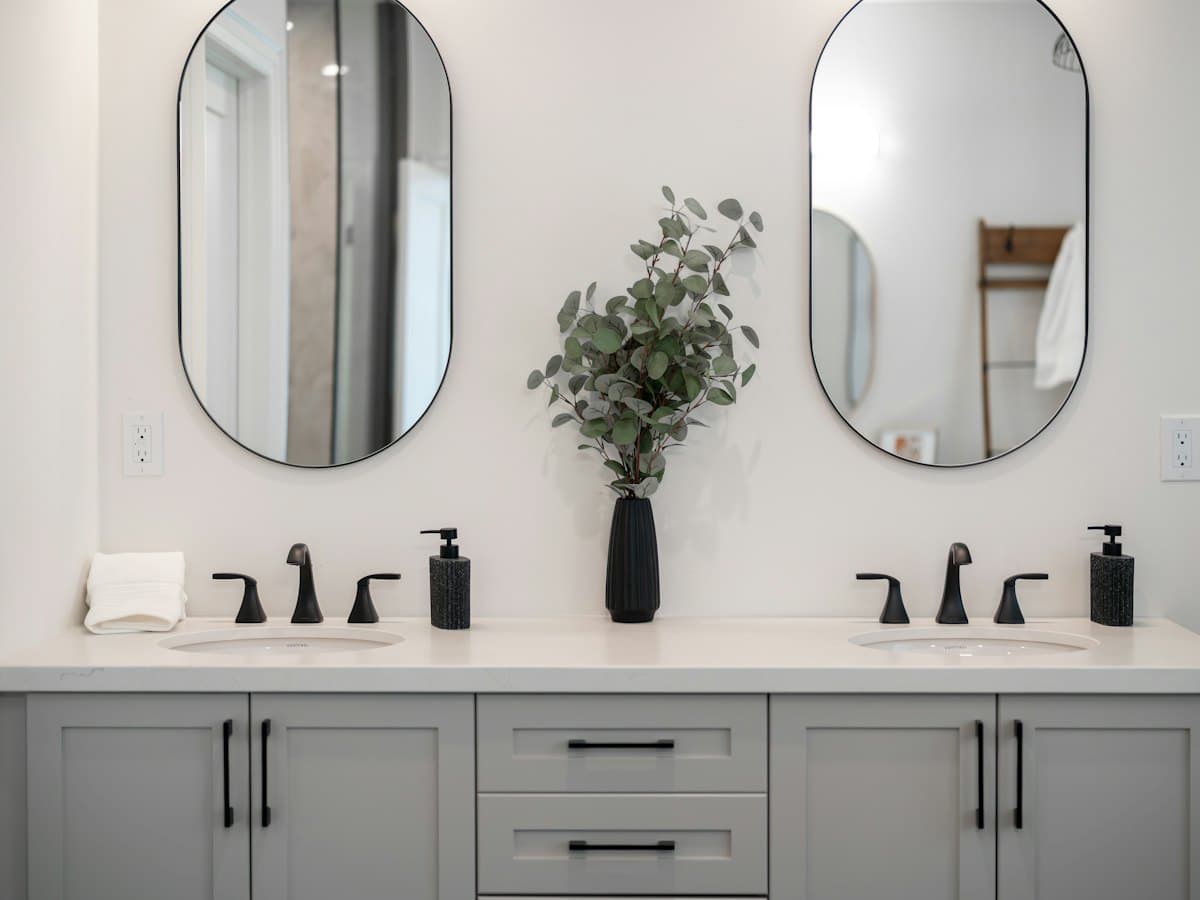 A modern bathroom vanity with two sinks, mirrors and a wooden cabinet.